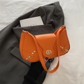 Orange faux leather baguette bag with gold studs and twist-lock on a suit background - Orange