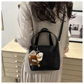 Detail of black lychee grain bucket bag featuring a plush charm and slim shoulder strap - Pendant Contact Customer Service