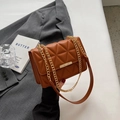 Brown geometric quilted handbag with gold chain strap in a lifestyle setting - Brown