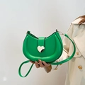 Borsa a sella verde alla moda con fibbia a forma di cuore tenuta da una modella - Oro Cuore Passante / Verde