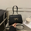 Elegante bolso de mano trapezoidal negro con lazo de metal dorado y bandolera - Negro