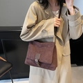 Deep brown suede crossbody bag with vintage buckle detail shown on a khaki trench coat - Brown