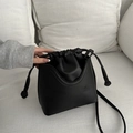 Minimalist black drawstring bucket bag with a matte leather finish and slim shoulder strap - Black