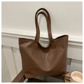 Detail of a large brown faux leather tote bag on a wooden table next to a coffee cup - Brown