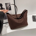 Bruine suède onderarm draagtas met slanke schouderriem en een minimalistisch design - koffiekleur