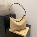 Minimalistische beige suède onderarmtas met slanke bruine schouderriem op boeken - Khaki