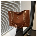 Detalle de un bolso tote retro de ante marrón oscuro con cadena dorada y colgante - Marrón