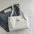 White corduroy tote bag with vertical texture and Fashion Instinct tag on denim background - White