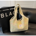 Detail shot of a soft fuzzy knit tote bag with colorful blended yarn on black sofa - Yellow