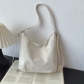 Detail einer cremeweißen Ledertasche mit Reißverschluss und ovalem Lederemblem - Einfache Tote Bag / Gebrochenes Weiß