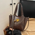 Braune Vintage Lederhandtasche mit goldenem Dreieckslogo und einem Glockenanhänger - Kaffeebraun mit Anhänger
