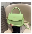 Detail of light green PU leather saddle bag with gold logo on a beige chair - Green