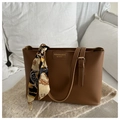 Detail of brown leather tote bag featuring an accent silk scarf and metal buckle handles - Tan