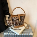 Leopard print bucket bag with brown leather handles and plush charm on white surface - With Pendant / Brown