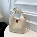 Detalle del bolso tote crema con hebilla de cuero marrón y costuras de asa reforzadas - Blanco