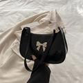 Chic black patent leather shoulder bag with a gold bow buckle in a minimalist design - Black