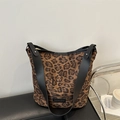 Borsa tote leopardata con ampi spallacci neri appoggiata su un divano in pelle nera - Leopardo Marrone