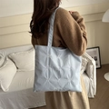 Light blue corduroy tote bag with white letter embroidery worn by model in home setting - Blue