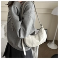 Elegante bolso de media luna blanco crema con costuras verticales en un ambiente interior - Blanco