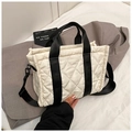 Detalle de bolso tote acolchado blanco con asas negras sobre una chaqueta gris - Blanco