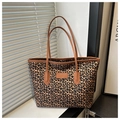 Close-up of leopard print canvas tote bag with brown leather handles and rectangular patch - Brown