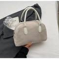 Detail einer beigen Wildleder-Muscheltasche mit weißen Ledergriffen in edlem Design - Gebrochenes Weiß