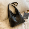 Bolso tote negro minimalista en cuero PU con correa ajustable sobre fondo de textura - Negro