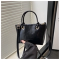 Detail of glossy black leather bucket bag featuring elegant gold hardware and thin straps - Black