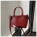 Detail of burgundy mini bucket bag with leather texture and gold hardware accents - Red