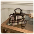 Close-up of vintage plaid bucket bag with brown leather straps and gold rivets - Brown