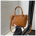 Close-up of bright brown bucket bag with FASHION & BAGS engraving and gold hardware - Brown