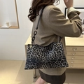 Large leopard print tote bag with thick chain strap shown on model in olive suit - Black