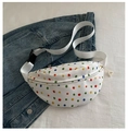 Détail d'un sac banane blanc en toile à pois colorés posé sur une veste en jean - Blanc