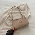 Elegant beige baguette underarm bag with gold bow clasp on neutral blazer background - Khaki