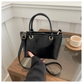 Black patent leather bucket bag with top handles and shoulder strap on a wooden table - Black (Without Charm)