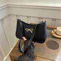 Minimalist black baguette shoulder bag with gold bow detail and matte leather finish - Black
