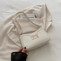 Chic white leather underarm bag with elegant gold bow buckle on a beige blazer - White