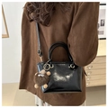 Detail der glänzenden schwarzen Lackleder-Beuteltasche mit süßem Plüschbär-Anhänger - Schwarz (Mit Braunem Monster-Anhänger)
