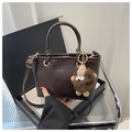 Detail of dark brown glossy PU bucket bag with plush charm and adjustable strap - Brown (With Brown Monster Pendant)