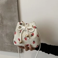 Chic cream bucket bag featuring red strawberry prints and a white drawstring rope strap - White Strawberry