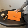 Minimalist orange bow clutch bag with a sleek envelope design and wrist strap - Orange