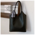 Detail of black pebbled leather tote bag with a checkered silk scarf on a wooden shelf - Black