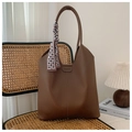Detail of a brown leather bucket bag with silk scarf on a vintage wicker chair - Coffee