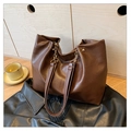 Dettaglio borsa tote in ecopelle marrone scuro con catena oro su giacca nera - caffè