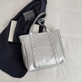 Metallic silver leather tote bag with dual handles and front pocket on white fabric - Silver