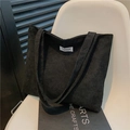 Black corduroy tote bag with fashion label on a white chair, spacious for commuting - Black