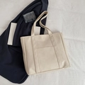Minimalist beige PU leather tote bag with front pocket on white fabric background - White