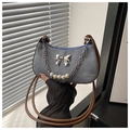 Detail of denim crescent bag featuring silver bow charm and pearl chain accent - Blue