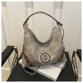 Detail of taupe canvas tote with leather straps and silver M logo on a black chair - No Pendant / Khaki
