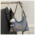 Dettaglio della borsa denim grigio-blu con finiture in pelle marrone e logo M in metallo - Blu Con Pendente a Nuvola